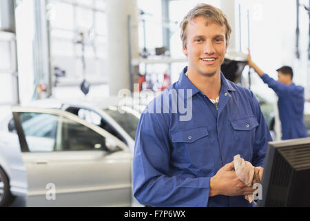 Portrait smiling mechanic at computer in auto repair shop Banque D'Images