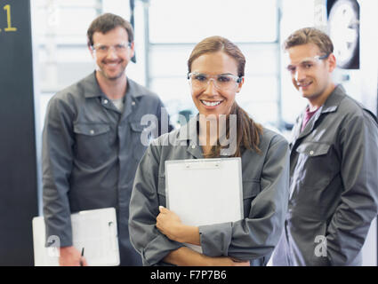 Portrait confident female mechanic with clipboard in auto repair shop Banque D'Images