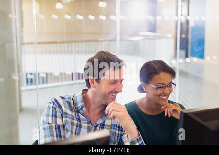 Smiling businessman and businesswoman working at computer in office Banque D'Images