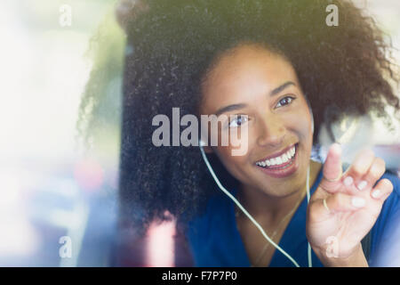 Femme souriante avec afro et des écouteurs en forme de coeur dessin sur bus window Banque D'Images