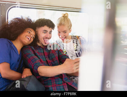 Amis ludique en tenant des selfies visages sur le bus Banque D'Images