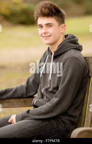 Teenage boy sitting on a park bench Banque D'Images