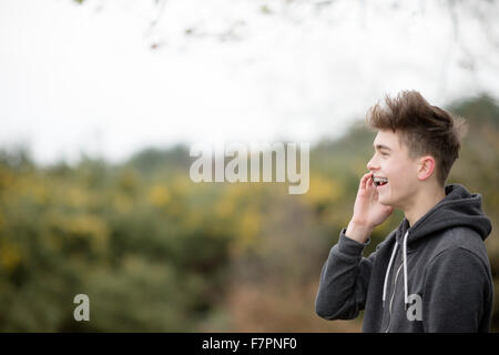 Teenage boy en utilisant son téléphone portable en plein air Banque D'Images