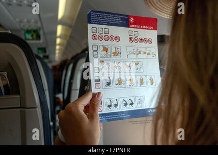 La sécurité à bord, la femme lit la carte d'instructions de sécurité à bord. Airbus A320. Banque D'Images