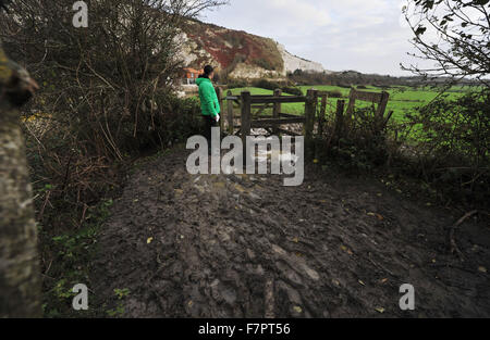 Homme marchant le long d'un chemin boueux le long de berges de la rivière Ouse Lewes en hiver Banque D'Images