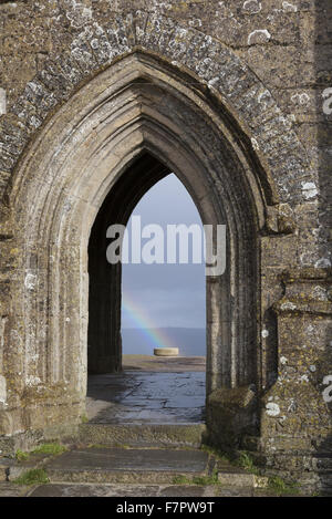 Vue à travers la porte voûtée de St Michael's Tower, le Tor de Glastonbury, Somerset, avec un arc-en-ciel vu au-delà. La tour est la seule partie restante de l'église de St Michel, qui a été construit au xve siècle. Banque D'Images