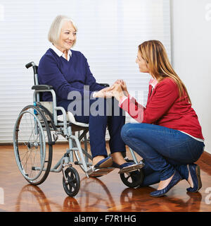 Smiling senior woman in wheelchair with daughter holding hands Banque D'Images