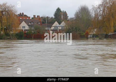 Une vue à travers une rivière gonflée à la recherche dans un grand hôtel de l'autre côté avec inondé de halage et un ciel noir. Banque D'Images