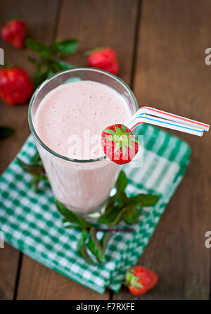 Lait frappé aux fraises smoothie avec des fraises fraîches sur un fond de bois. Banque D'Images