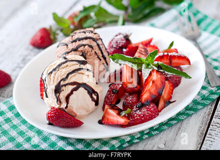 La crème glacée avec des fraises et du chocolat sur une plaque blanche Banque D'Images