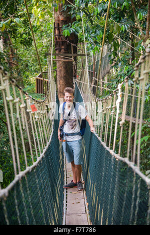 Jeune homme tourisme ou un pont suspendu dans la jungle, Canopy Walkway, Kuala Tahan, Taman Negara, Malaisie Banque D'Images