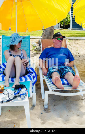 A 50 ans caucasien couple chaises de plage et parasols sur la plage de Sainte Croix, Îles Vierges des États-Unis. USVI, U.S.V.I. Banque D'Images