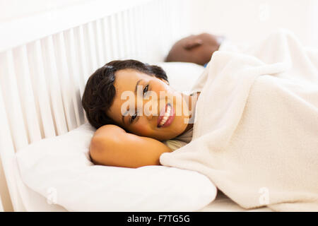 Happy young woman lying on bed à côté de mari Banque D'Images