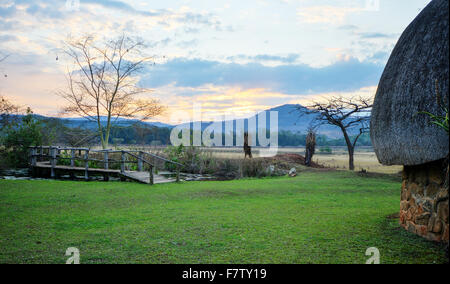 Coucher du soleil à Mlilwane Game Reserve avec une hutte Swazi traditionnel Banque D'Images