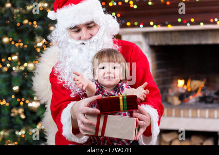 Noël et l'enfance concept - smiling boy enfant avec le père Noël et les cadeaux plus de lumières fond Banque D'Images