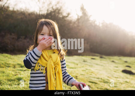 Laughing girl avec la main devant la bouche, holding mobile phone Banque D'Images