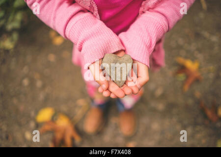 Girl holding heart shape stone Banque D'Images