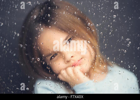 À la fille par la fenêtre un jour de pluie Banque D'Images