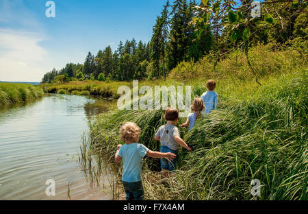 Quatre enfants marcher dans l'herbe haute Banque D'Images