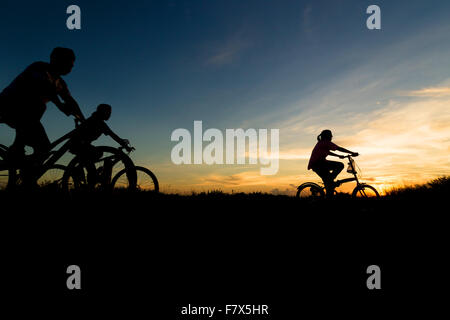 Silhouette of family vélo au coucher du soleil Banque D'Images