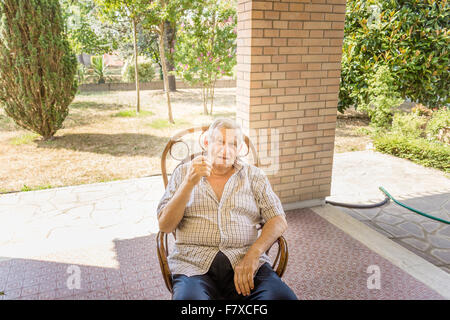 Personnes âgées L'octogénaire homme assis sur une chaise sur la terrasse de la chambre Banque D'Images