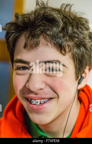 Close-up of a Teenage boy wearing earphones et montrant les accolades en souriant Banque D'Images