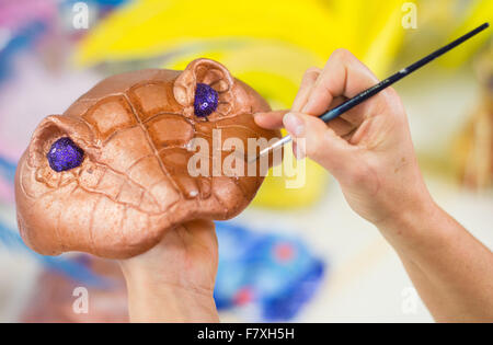 Hambourg, Allemagne. 19Th Mar, 2015. Une femme peint un masque dans l'atelier de costumes pour la comédie musicale Disney Aladdin à Hambourg, Allemagne, 3 décembre 2015. La comédie musicale s'ouvre pour sa première Européenne le 6 décembre 2015 au théâtre Neue Flora à Hambourg. PHOTO : DANIEL BOCKWOLDT/DPA/Alamy Live News Banque D'Images