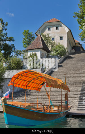 Sites touristiques bateau amarré sur le quai de l'île avec église de l'assomption de Marie sur le lac de Bled en Slovénie Banque D'Images