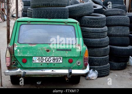 Vieille voiture verte à Bakou, Azerbaïdjan sous une pile et plein de pneus, de derrière Banque D'Images