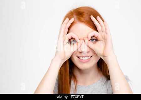 Portrait de jeune fille rousse ludique amusante faisant masque avec ses mains sur fond blanc Banque D'Images