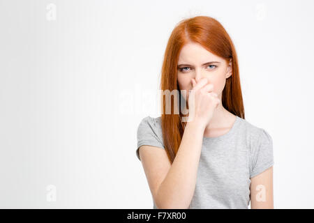 Belle jeune femme aux longs cheveux rouges a fermé son nez à la main isolated over white background Banque D'Images