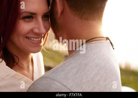 Close up shot of young woman embracing son petit ami et à la voiture en souriant. Jeune couple aimant l'extérieur. Banque D'Images