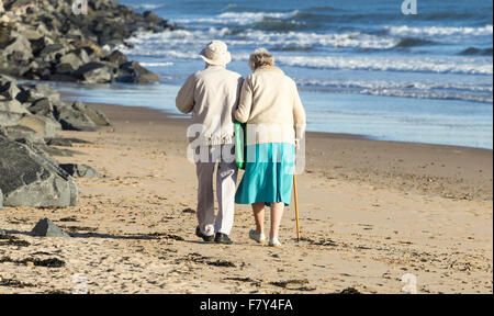 Vieux couple walking on beach. UK Banque D'Images