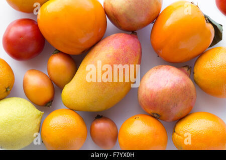 De nombreux fruits d'orange sur fond blanc - Oranges, Mangue, citron, kaki Banque D'Images