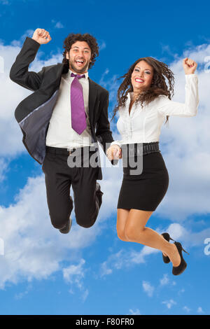 Un bel homme d'affaires et un gorgeous businesswoman jumping over a blue sky Banque D'Images