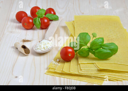 Les feuilles de lasagne avec des feuilles de basilic frais, tomates cerises, fromage râpé et la muscade, posé sur bureau cuisine Banque D'Images