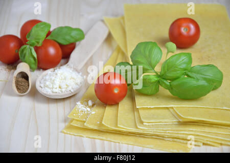 Les feuilles de lasagne avec des feuilles de basilic frais, tomates cerises, fromage râpé et la muscade, posé sur bureau cuisine Banque D'Images