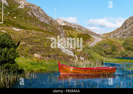 Un petit bateau voguant sur les eaux du Loch Dubh à Tarbet, Sutherland, Scotland. En août. Banque D'Images