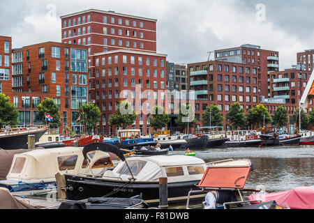 Petit port avec des bateaux et des maisons rouges typiques à Amsterdam Banque D'Images