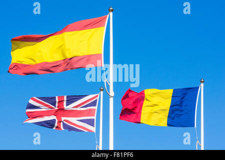 3 drapeaux battant pavillon roumain spanish flag union jack flag against blue sky Banque D'Images