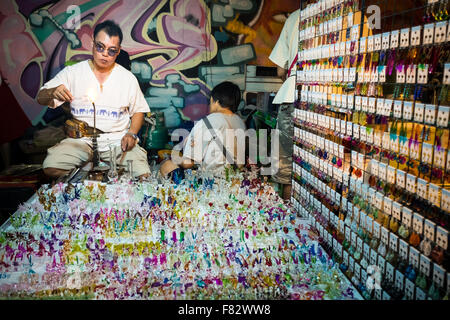 Un homme faire verre souvenirs au marché de nuit à pied le long de Wualai Road à Chiang Mai, Thaïlande. Banque D'Images