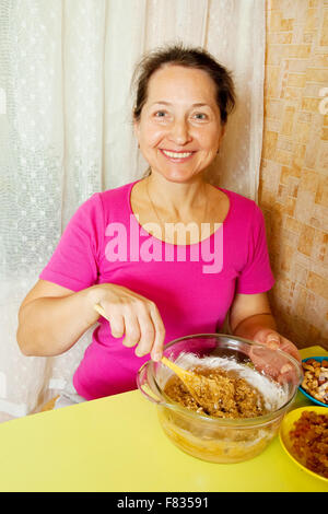 Femme mature en pâte dans le plat. L'une des étapes de la cuisson du gâteau au miel. Voir la série Banque D'Images