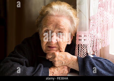 Vieille Femme assise près de la fenêtre, un portrait en gros plan. Banque D'Images