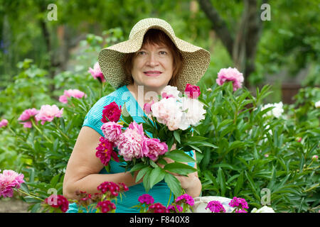 Female gardener en usine au jardin de pivoines Banque D'Images