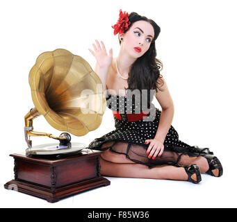 Jolie fille à l'écoute de la musique sur vieux gramophone isolé sur blanc en studio Banque D'Images