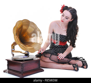 Jolie fille à l'écoute de la musique sur vieux gramophone isolé sur blanc en studio Banque D'Images