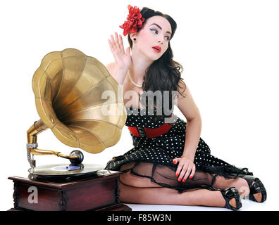 Jolie fille à l'écoute de la musique sur vieux gramophone isolé sur blanc en studio Banque D'Images