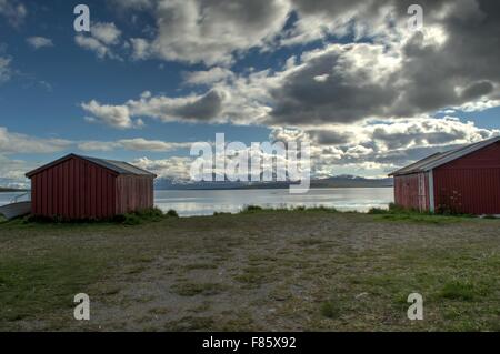 Old Red les hangars à bateaux en été avec la montagne enneigée et bleu fond du fjord Banque D'Images