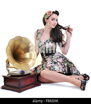 Jolie fille à l'écoute de la musique sur vieux gramophone isolé sur blanc en studio Banque D'Images