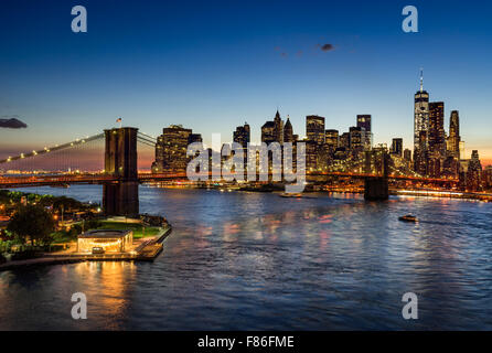 Pont de Brooklyn et Manhattan illuminée au crépuscule. Quartier des gratte-ciel de refléter dans l'East River, New York. Banque D'Images